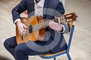 Men playing guitar Handsome young men sitting on chair and playing acoustic guitar