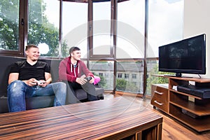 Men playing video games while sitting on sofa