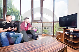 men playing video games while sitting on sofa