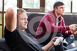 men playing video games while sitting on sofa