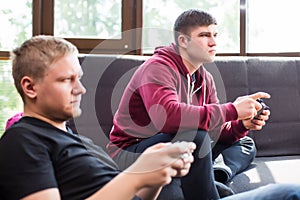 Men playing video games while sitting on sofa