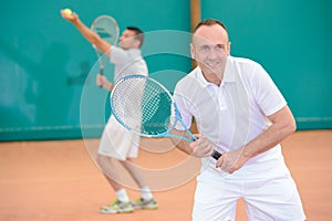 Men playng tennis doubles