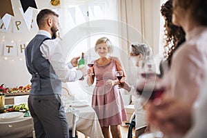 A man pouring guests wine on a indoor family birthday party.