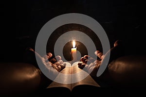 Men praying on the Bible in the light candles selective focus