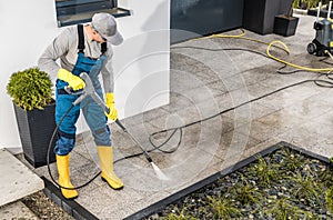 Men Pressure Washing His House Surrounding