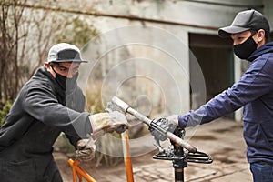 Men removing the paint of an orange bicycle frame during a bike renovation work