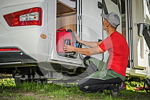 Men Removing Portable Gas Generator From His Camper Van RV Storage Area