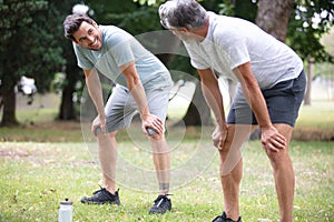 men resting leaning on their legs after exercising