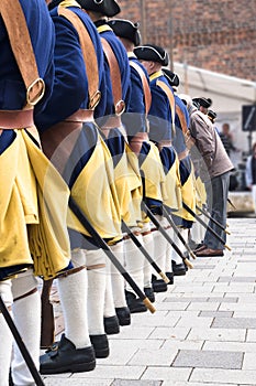 Men in a row from behind wear historical swedish soldier uniform