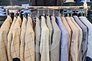 Suits hanging on the wooden clothes hanger of man cloth store with a cosy and businessman style. Official men wear in shop