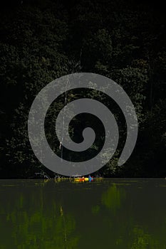 Men rowing on boats on a scenic lake surrounded by the leafy trees of a dense forest