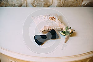 Men`s accessories, bow tie, wedding golden rings, boutonniere on a white table. Businessman clothing detail concept