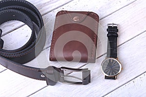 Men`s accessories for business and rekreation. Leather belt, wallet, watch and smoking pipe on wood background.. Top