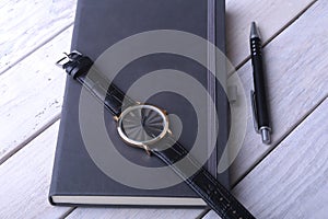 Men`s accessories for business and rekreation. Leather notebook, watch and pen on wood background.. Top view composition.