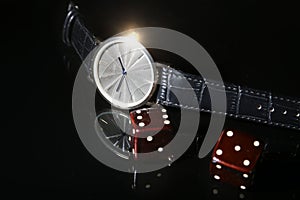 Men`s accessories for business and rekreation. Watch and dice on black mirror background.. Top view composition.