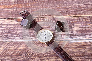 Men`s accessories for business and rekreation. Watch and dice on wood background.. Top view composition.