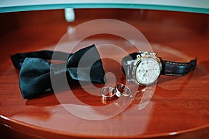 Men`s accessories for groom at wedding: watches, bow tie and rin