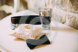 Men`s accessories, leather belt, perfume, bow tie, groom`s golden rings, watches and brides on a white table