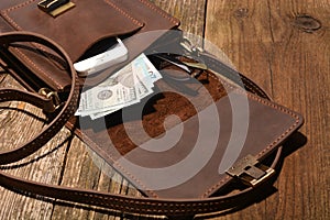 Men`s accessories- a  leisure bag, money, smartphone and glasses on a wooden board background
