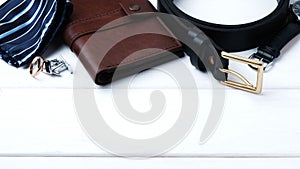 Men`s accessories - wallet, belt, cufflinks, watch, tie clip, handkerchief and ring on a white wooden background