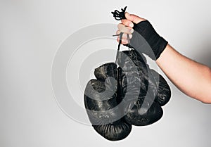 men's arm wrapped in a black elastic sports bandage holds old vintage leather boxing gloves