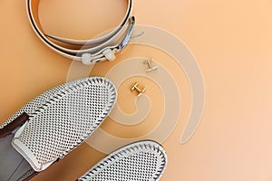 Men`s belt, shoes, cufflinks on beige background.