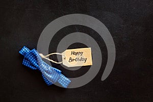 Men`s birthday concept. Happy birthday text and bow tie on black background top view copy space