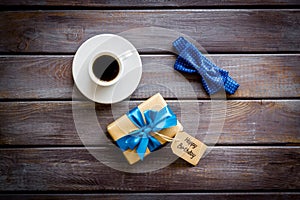 Men`s birthday concept. Happy birthday text, present box, bow tie and coffee on dark wooden background top view