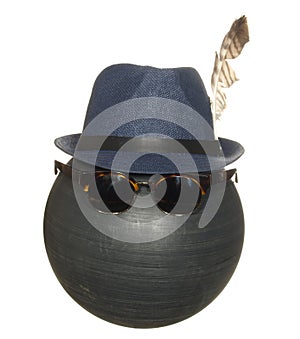Men`s blue hat with a bird feather and dark safety glasses on a black plastic ball isolated on white background
