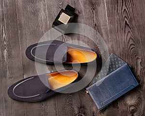 Men`s blue suede shoes are next to the perfume and cardholders on a dark wooden background