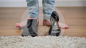 Men`s boot and women`s high heel shoe standing on the floor, male Caucasian feet coming up. Intersex person choosing