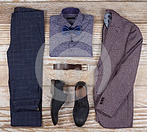 Men`s casual outfits for man clothing set with shoes, trousers, shirt, and bowtee on wooden background, Top view