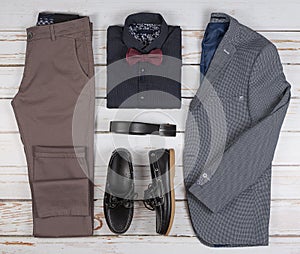 Men`s casual outfits for man clothing set with shoes, trousers, shirt, and bowtee on wooden background, Top view