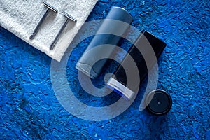 Men`s cosmetics for hair care and shaving. Shampoo, gel, razor, wax on blue background top view copyspace