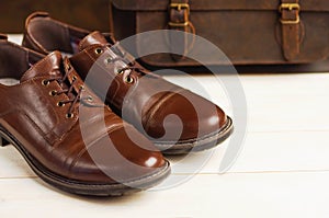 Men`s fashion with brown leather shoes and business bag on a wooden background. Men`s fashion, shoes, accessory, business backgr