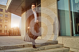 Men`s fashion. A young male businessman in a trendy suit and a white shirt with a big black handbag