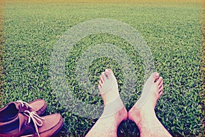 Men's feet ans shoes on the background of lush green grass ,vintage style photo