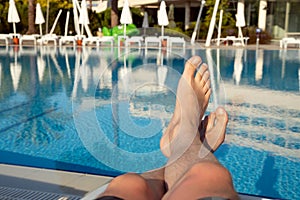 Men`s feet on the background of the swimming pool, relax on vacation