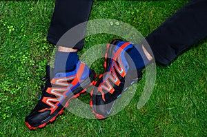 Men`s feet shod in a pair of red and blue sneakers