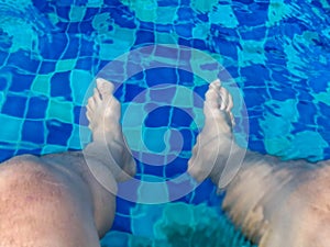 Men`s feet in the swimming pool