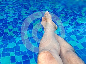 Men`s feet in the swimming pool