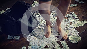 Men`s feet walk on a pile of dollars