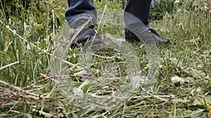 Men`s hand collects sloping grass closeup