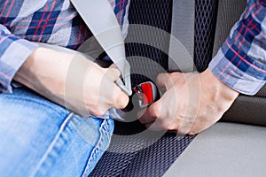 Men`s hand fastens the seat belt of the car