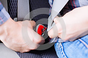 Men`s hand fastens the seat belt of the car