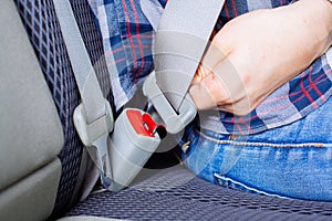 Men`s hand fastens the seat belt of the car