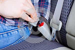 Men`s hand fastens the seat belt of the car