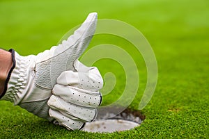 Men's hand in a glove golf shows OK near the hole