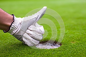 Men's hand in a glove golf shows OK near the hole