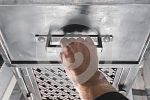 A men`s hand opens the handle of an iron cabinet or drawer